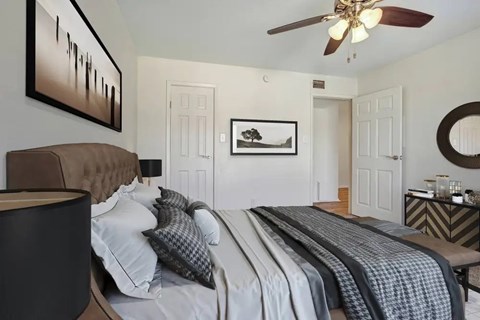 Bedroom with tufted headboard and ceiling fan at Village Green Apartments, San Marcos