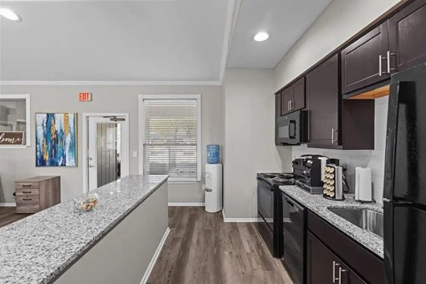 A kitchen with dark brown cabinets and a granite countertop.