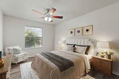 Bedroom with upholstered headboard and accent chair at Encino Park Apartments, Texas
