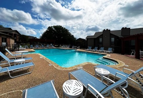 A pool surrounded by chairs and umbrellas.
