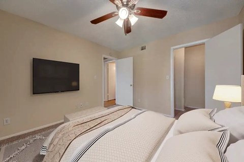 A bedroom with a large bed and a flat screen TV mounted on the wall.