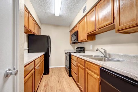 A kitchen with wooden cabinets and black appliances.