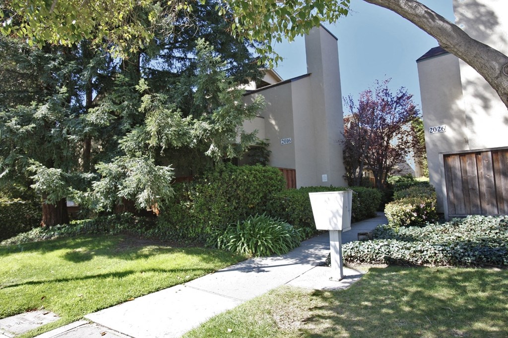 a sidewalk in front of a house with a mailbox