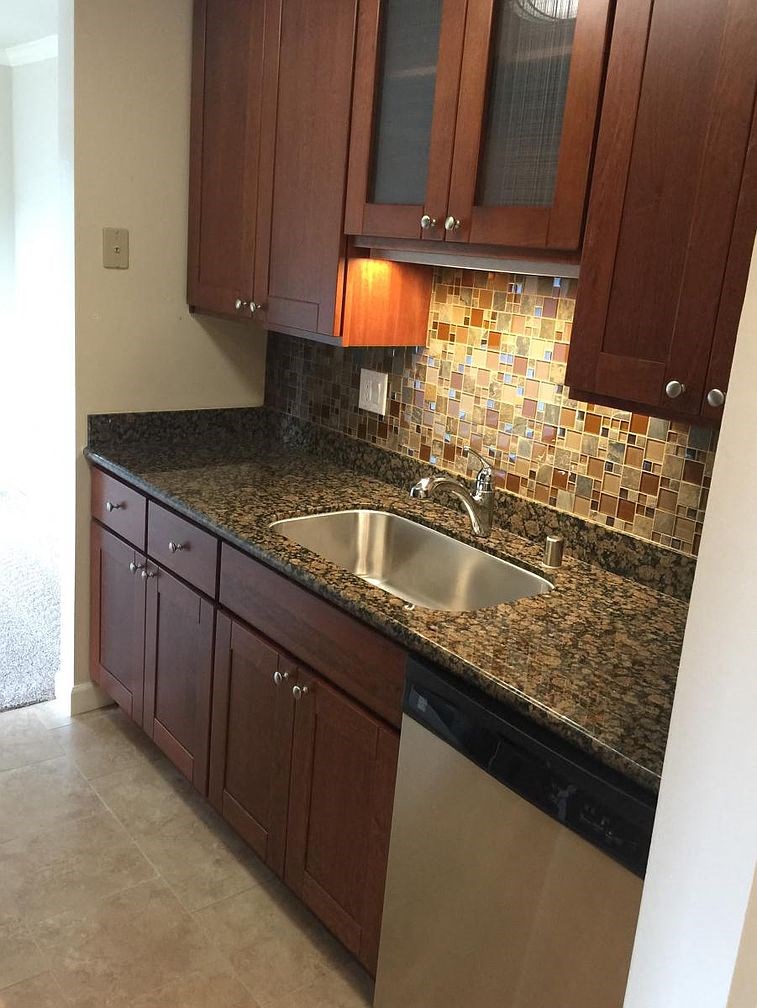 A kitchen with brown cabinets and a black counter top.