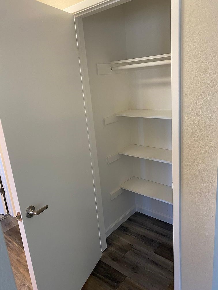 A white pantry with a door open.