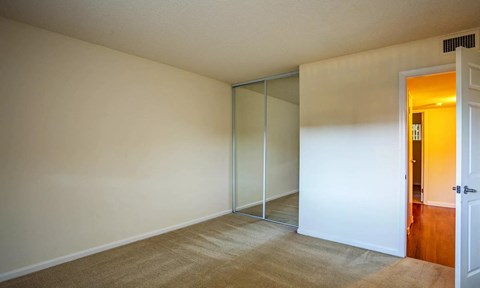 a bedroom with a mirrored closet and a door to a hallway