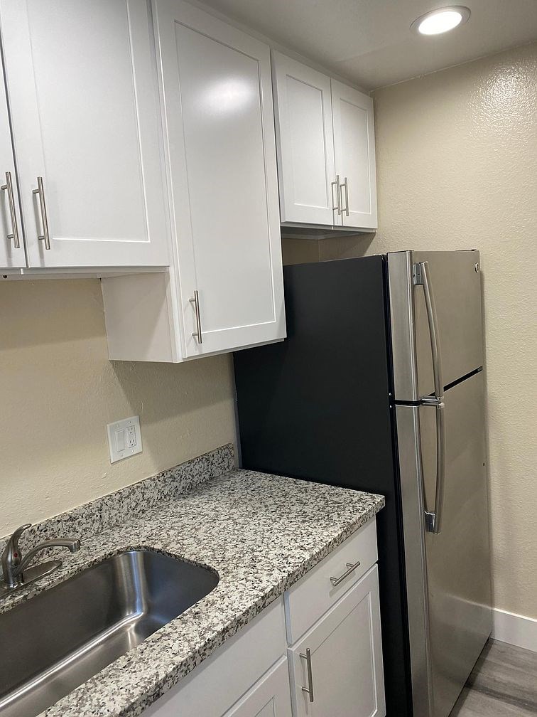 A kitchen with a black refrigerator and white cabinets.