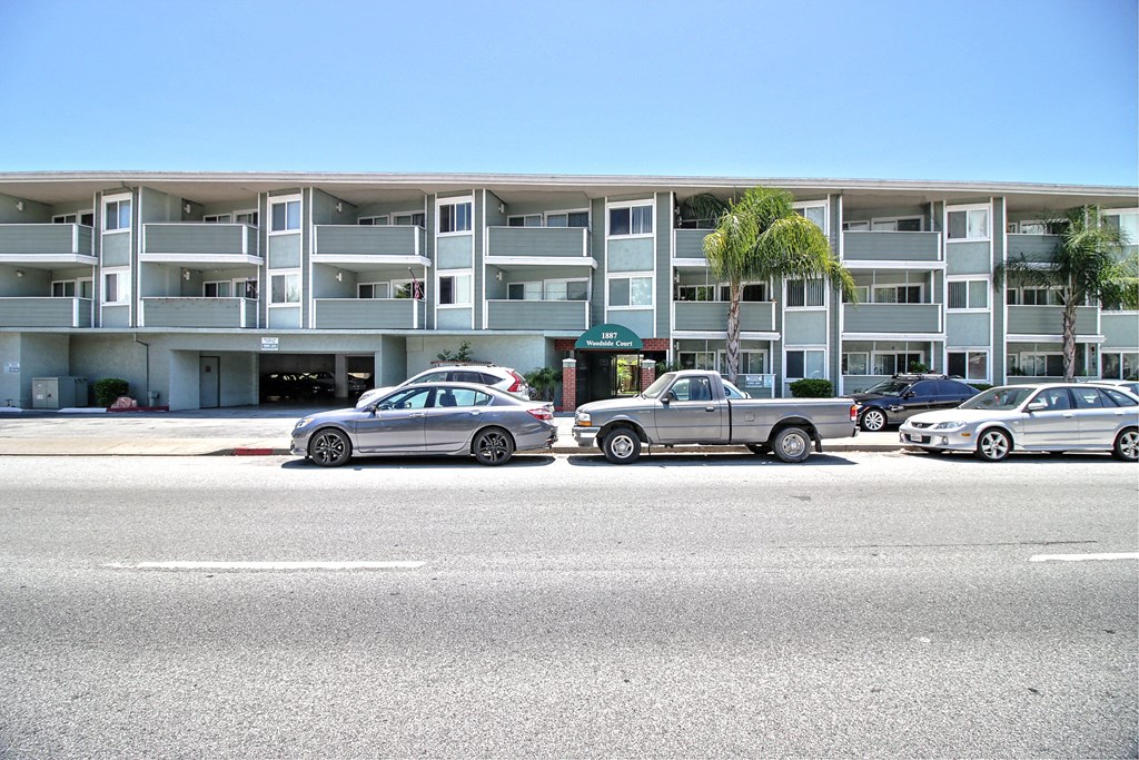 a city street with cars parked in front of an apartment building