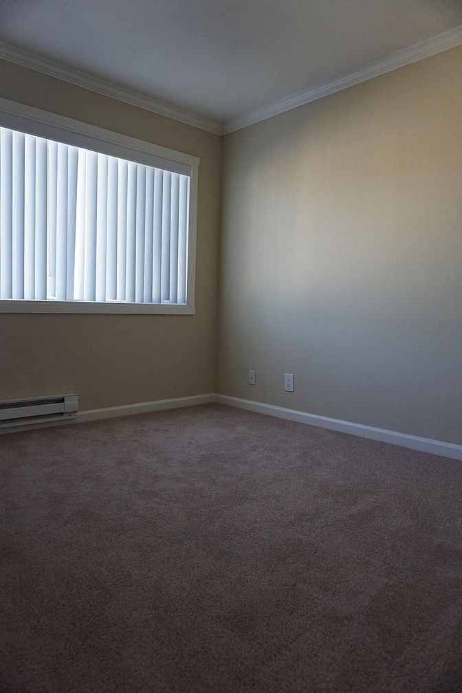 an empty room with a window and a carpet