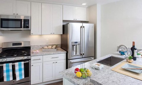 a kitchen with white cabinets and a stainless steel refrigerator