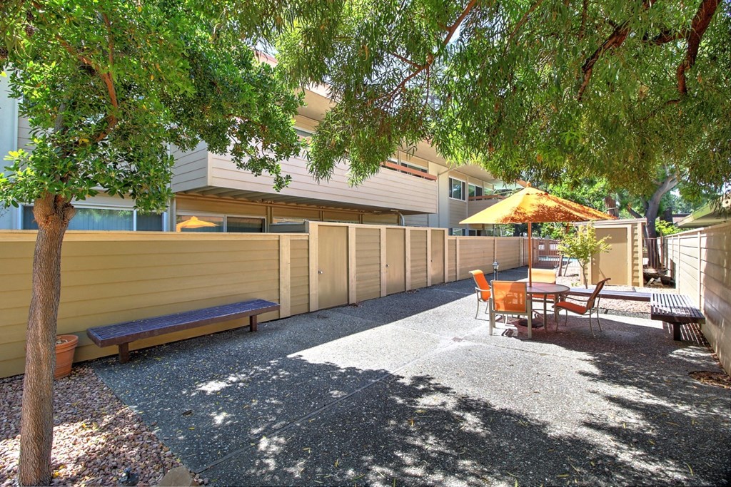a patio with a table and chairs and a fence