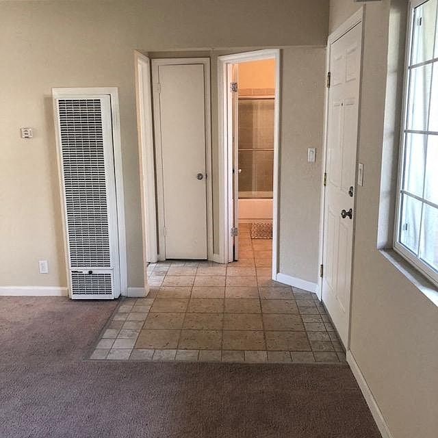A room with a carpeted floor, a door, and a window.