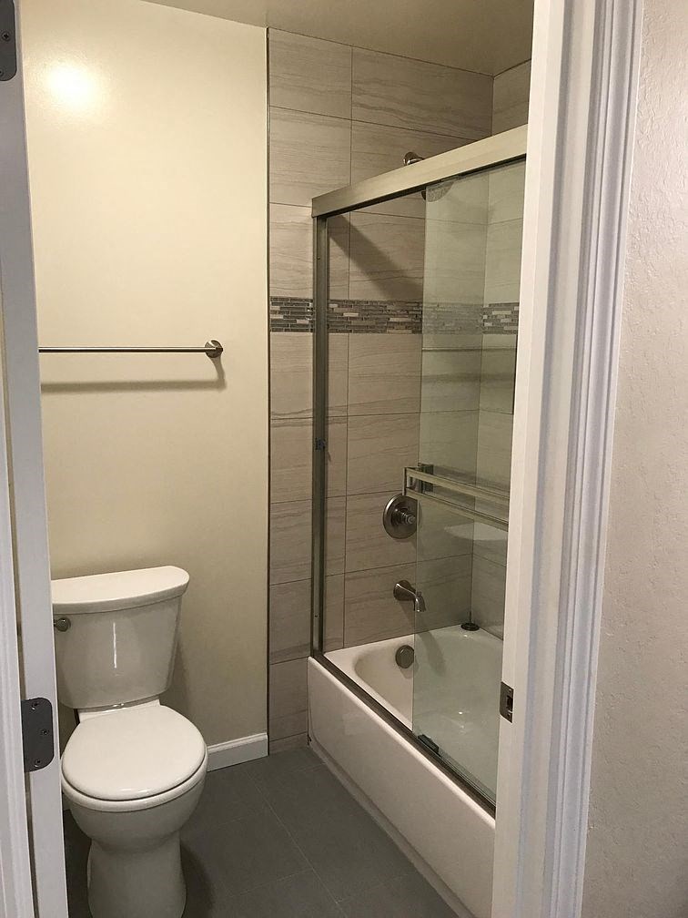 A white toilet is in a small bathroom with a glass shower door.