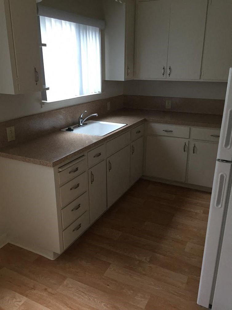 A kitchen with white cabinets and a white refrigerator.