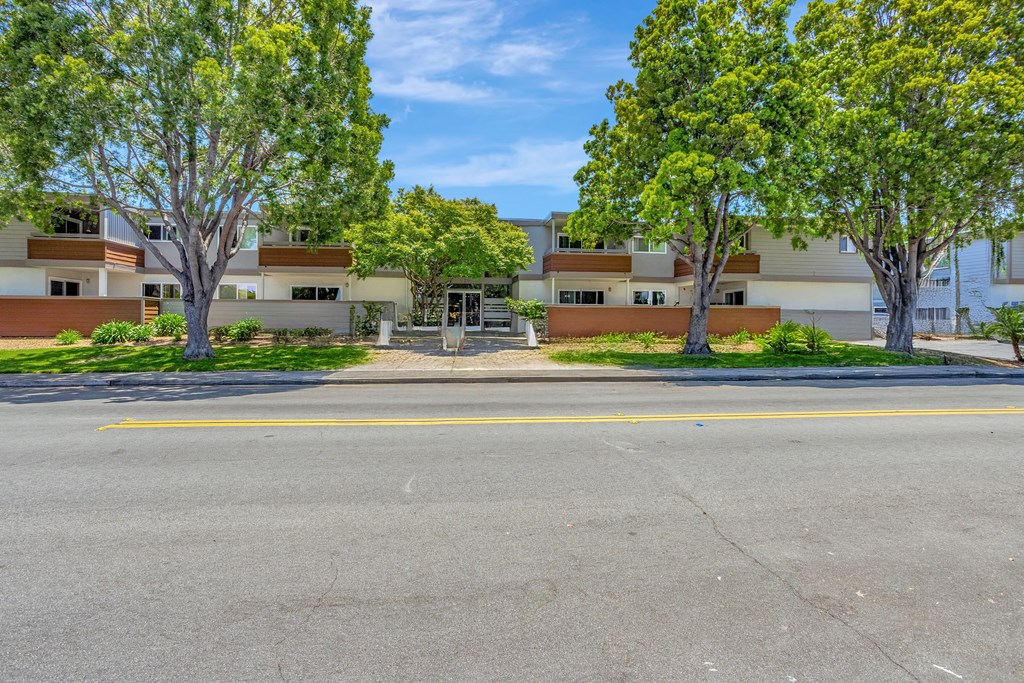 A street view of a residential area with houses and trees.