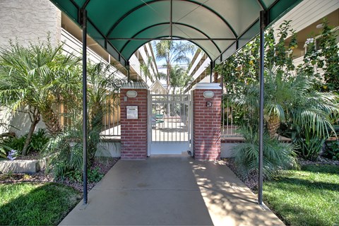 the entrance to a building with a white gate and a walkway with brick pillars