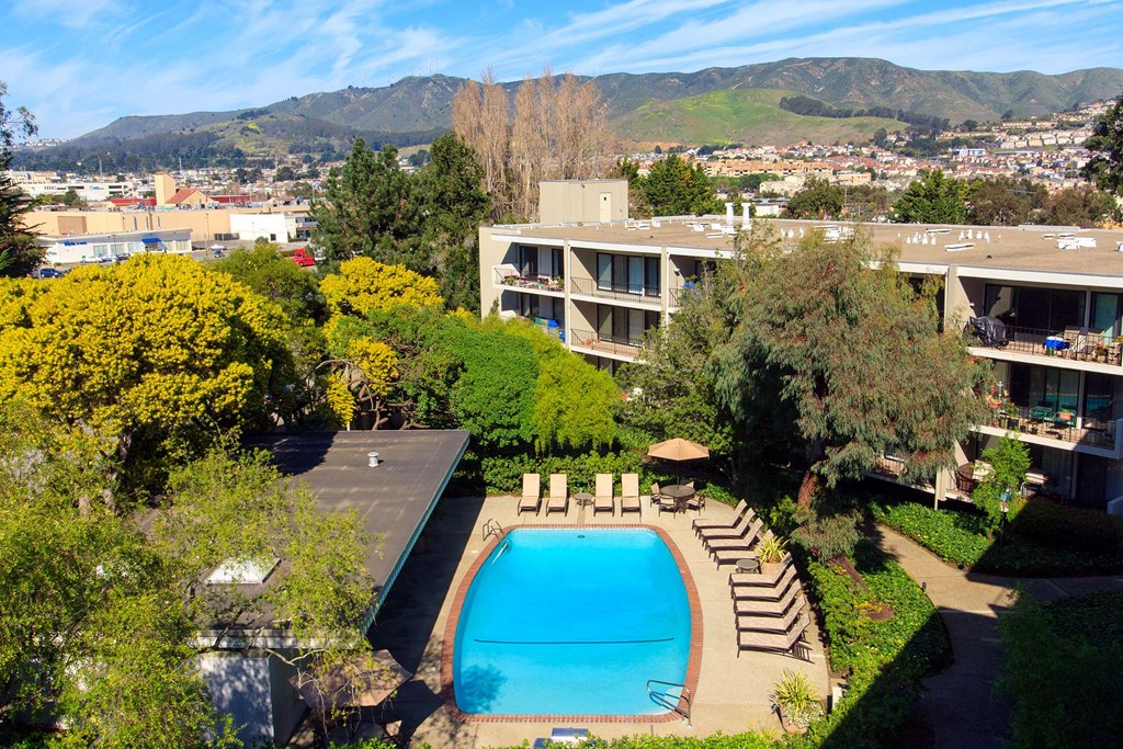 an aerial view of a swimming pool with a hotel in the background