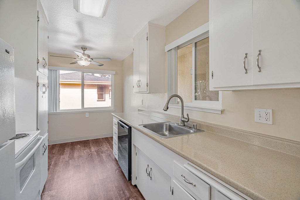 A kitchen with white cabinets and a marble countertop.