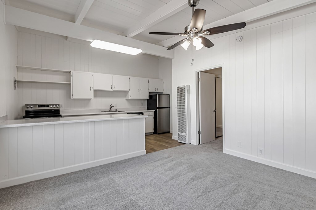 A kitchen with white cabinets and a fan on the ceiling.