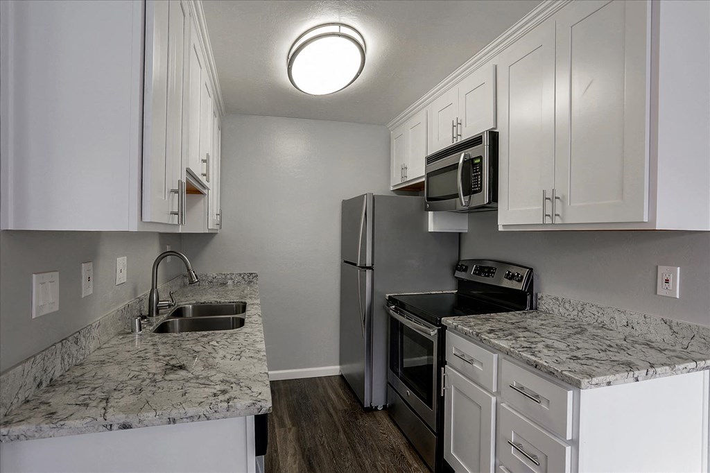 A kitchen with a marble counter top and stainless steel appliances.