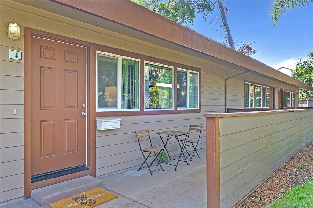 the front door of a home with a patio and chairs