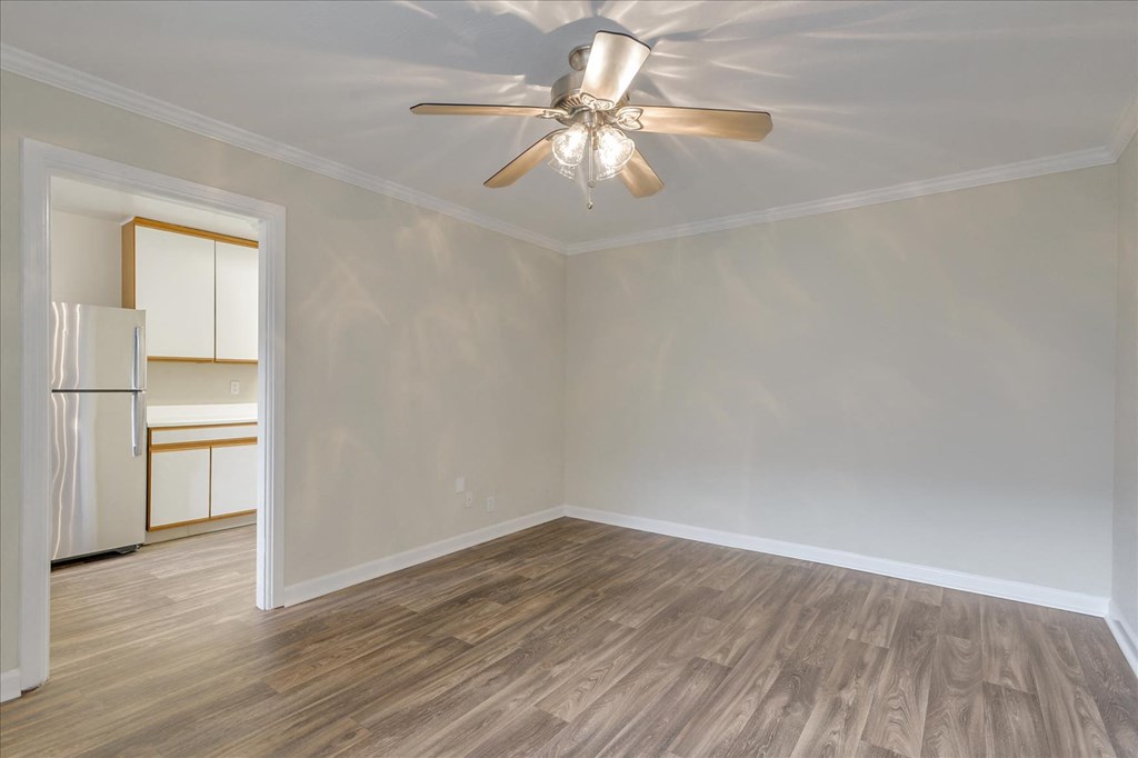 an empty living room with a ceiling fan and a kitchen