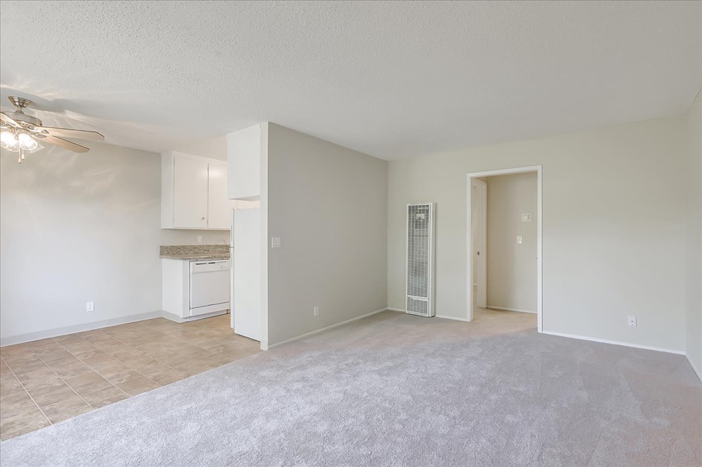 an empty living room and kitchen with a ceiling fan