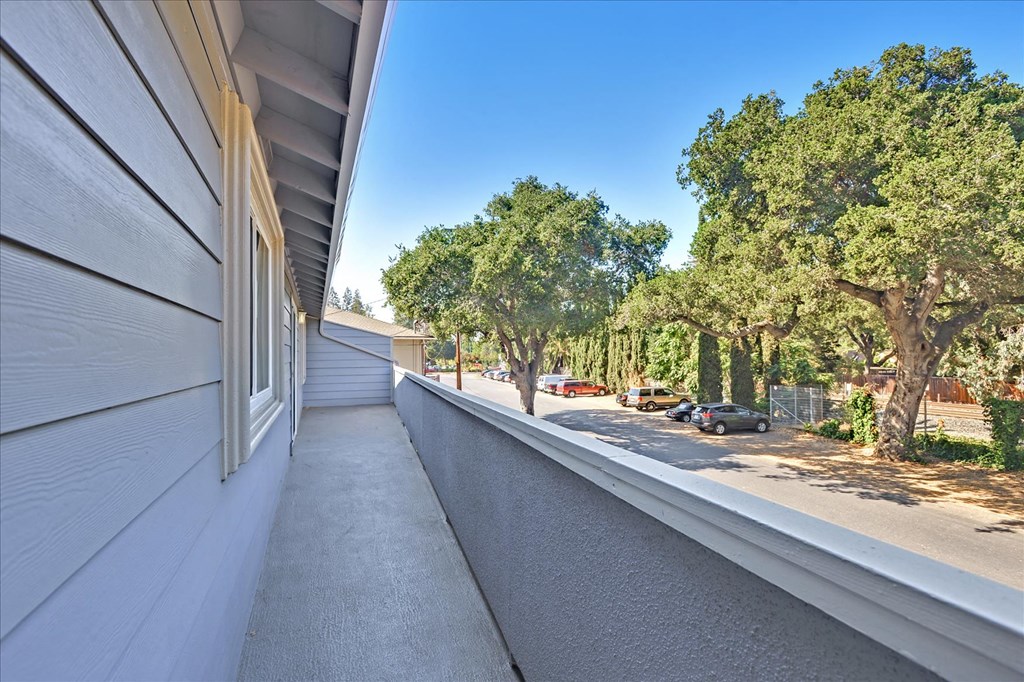 A long white building with a balcony overlooking a street.