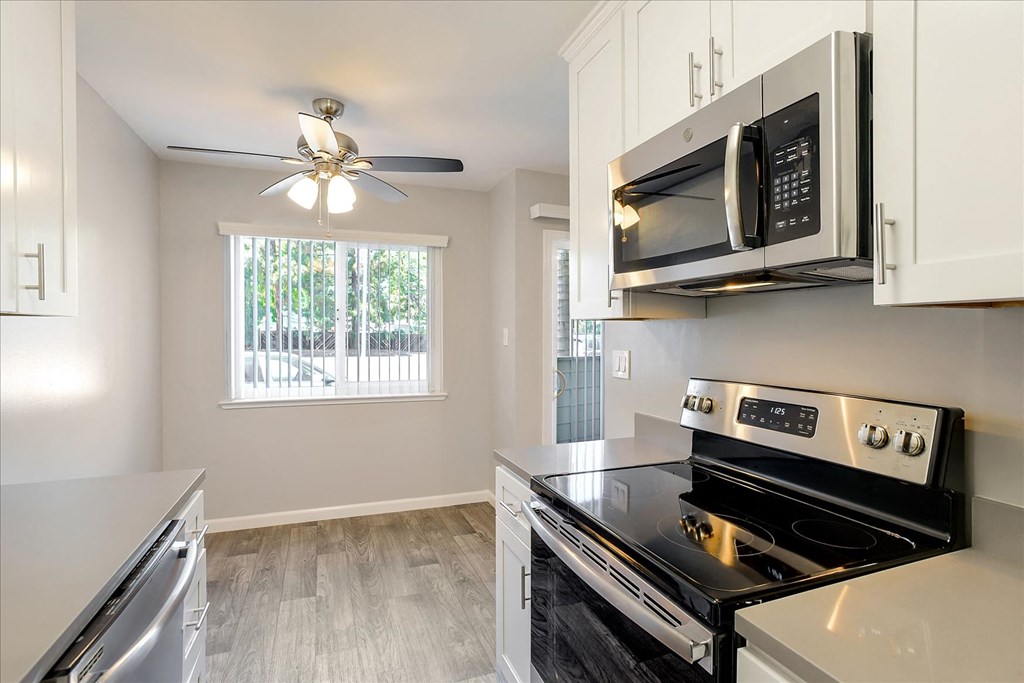 A modern kitchen with a black stove top oven and white cabinets.