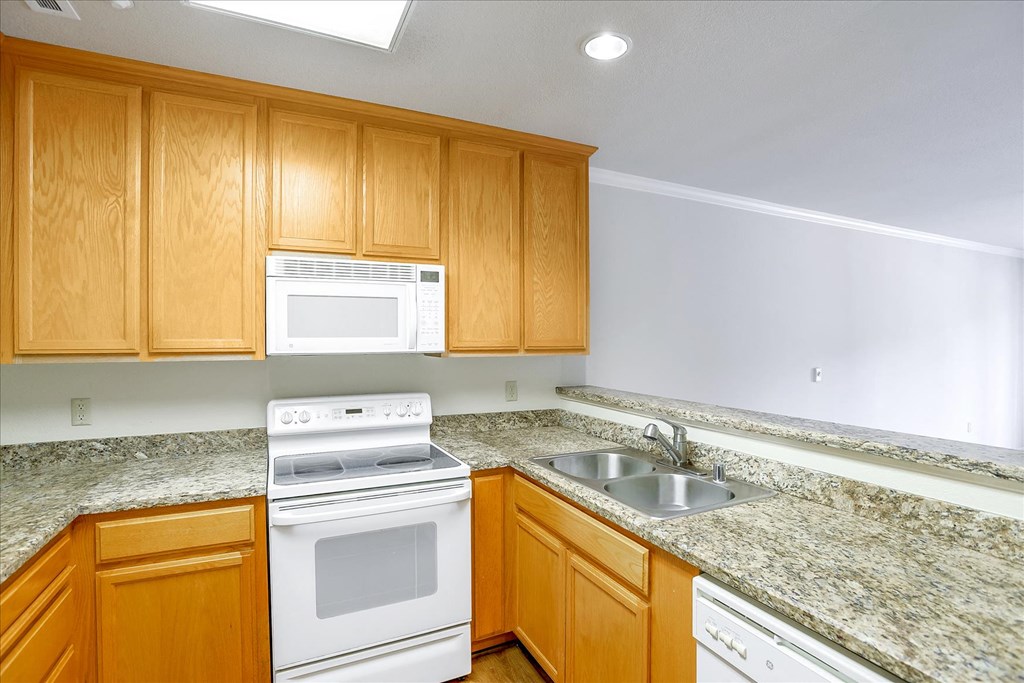 A kitchen with wooden cabinets and granite countertops.