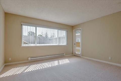 a room of an empty apartment with a large window