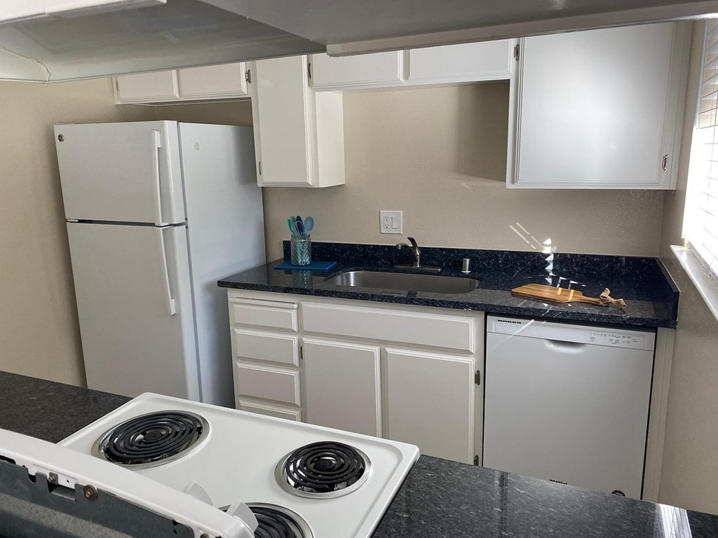 A white stove top oven in a kitchen with a black counter top.
