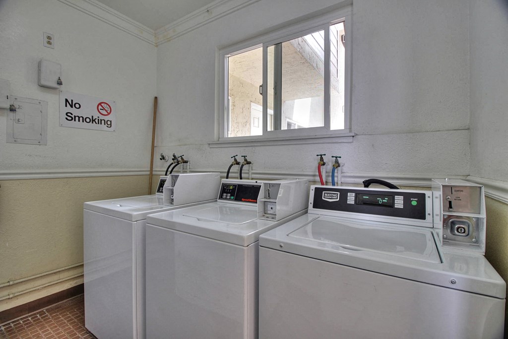 a laundry room with two washing machines and a dryer with a windwo