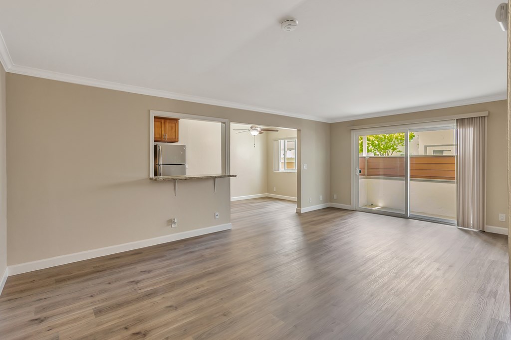 A spacious room with wooden flooring and a refrigerator built into the wall.
