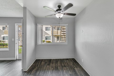 A room with a ceiling fan and a window overlooking a building.