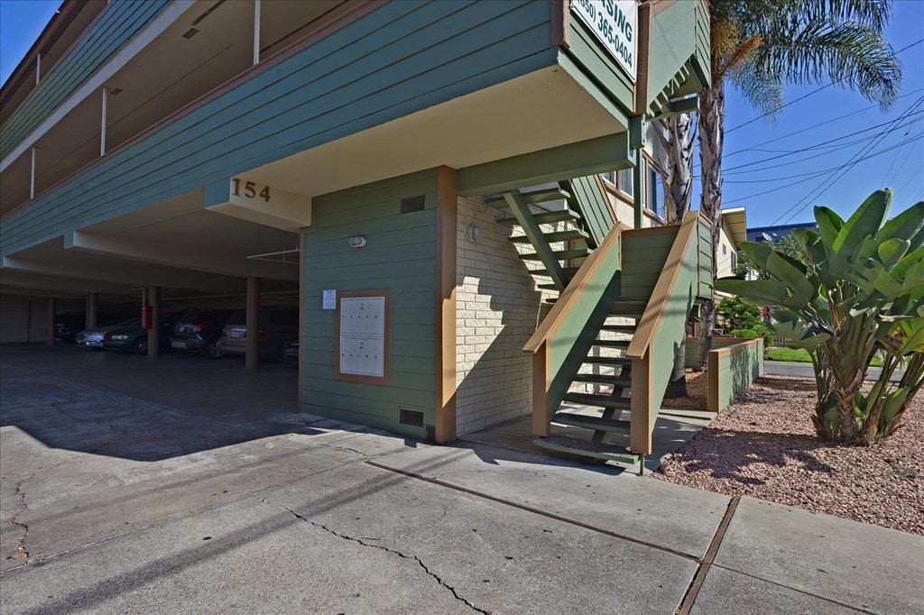 the front of a green building with stairs and a sidewalk