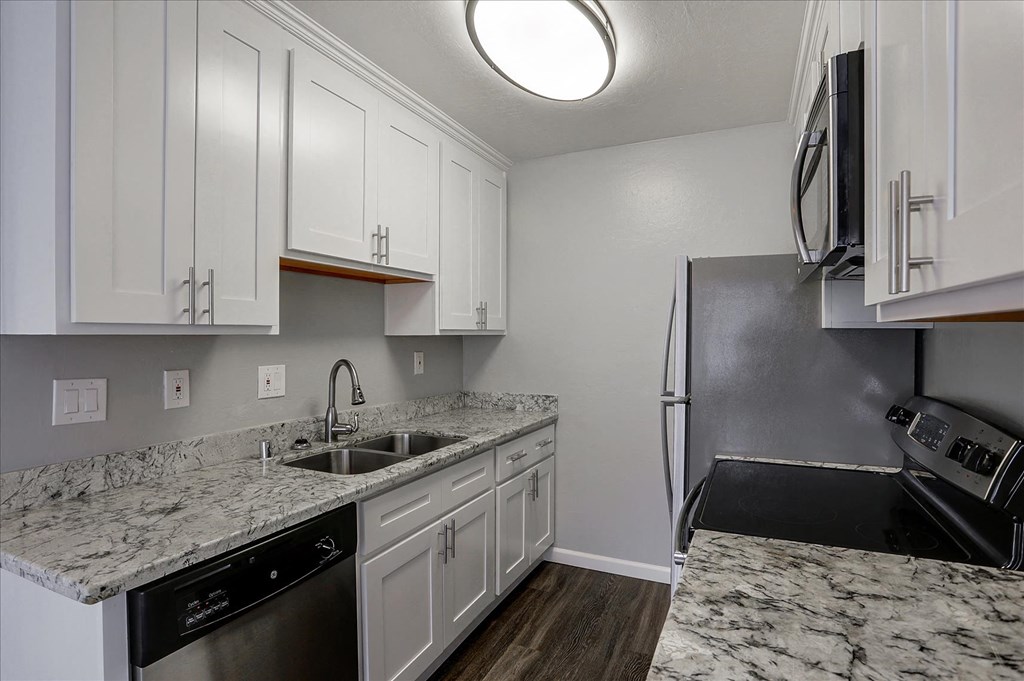 A kitchen with white cabinets and a marble countertop.