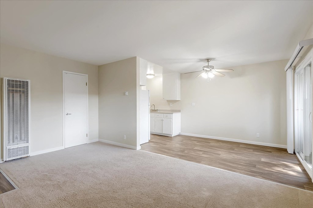 an empty living room and kitchen with a ceiling fan
