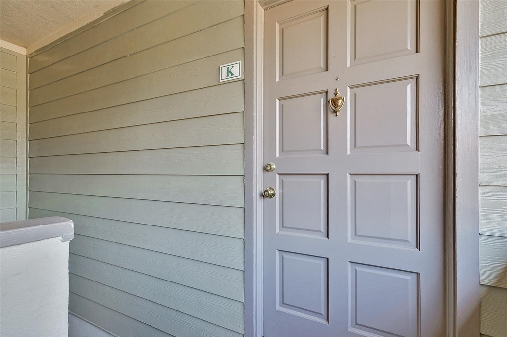 A white door with a keyhole is on the right side of a wall with horizontal siding.