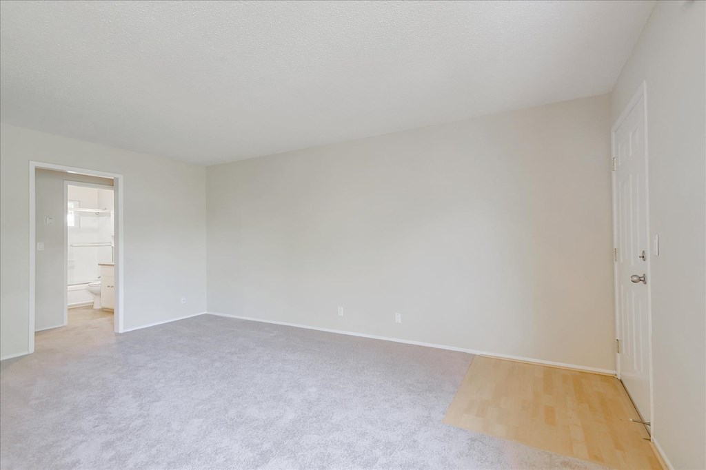 an empty living room with white walls and a hard wood floor