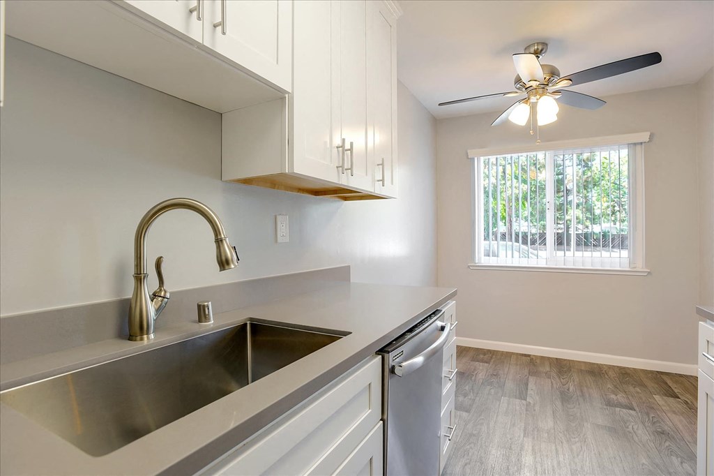 A modern kitchen with a stainless steel sink and a ceiling fan.
