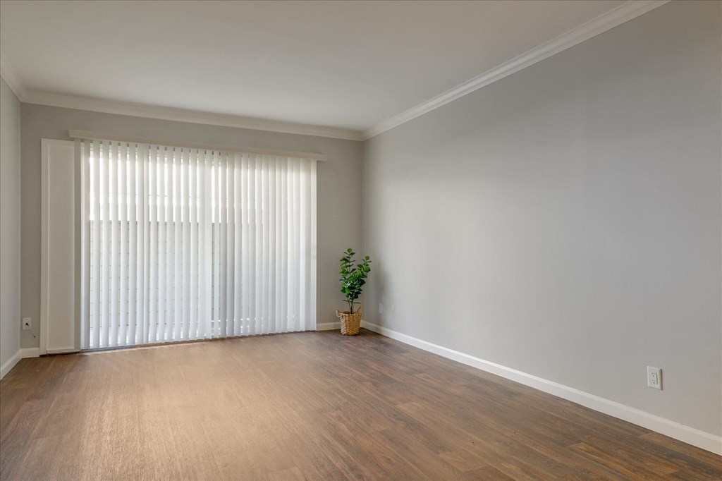 an empty living room with a large window and wood flooring