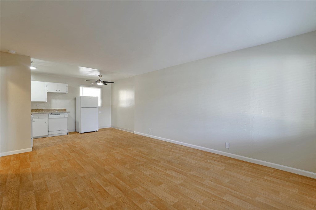 an empty living room and kitchen with wood floors