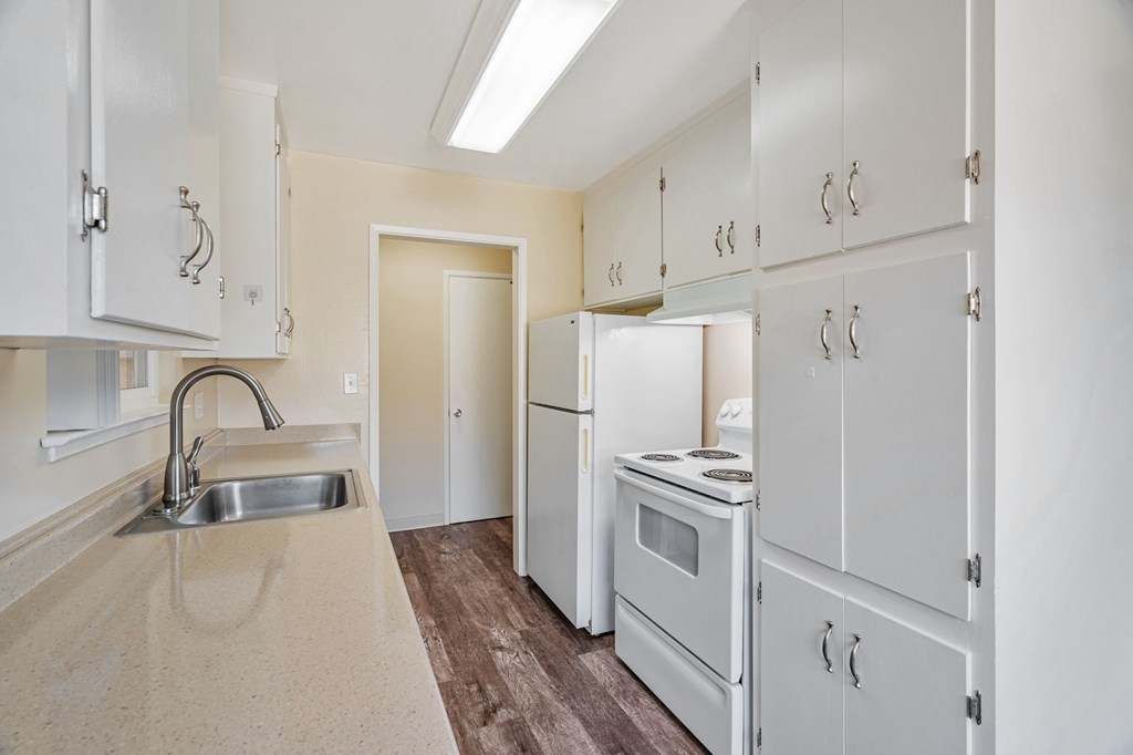 A kitchen with white cabinets and a stove top oven.