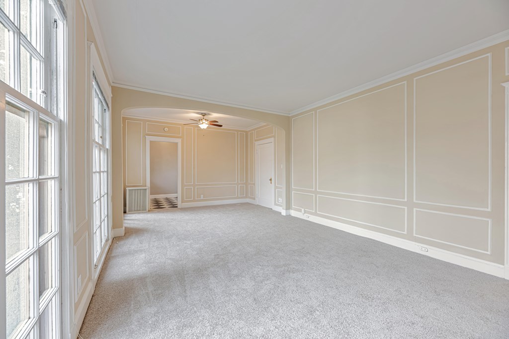 A large, empty room with white walls and carpeted floor.