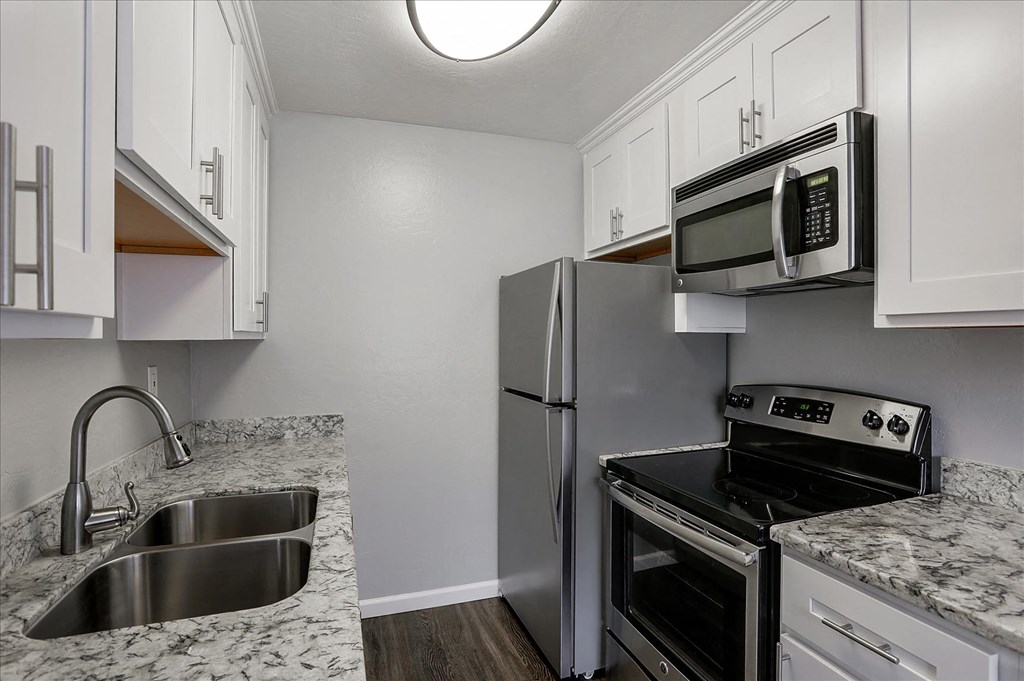 A kitchen with a sink, refrigerator, and stove.