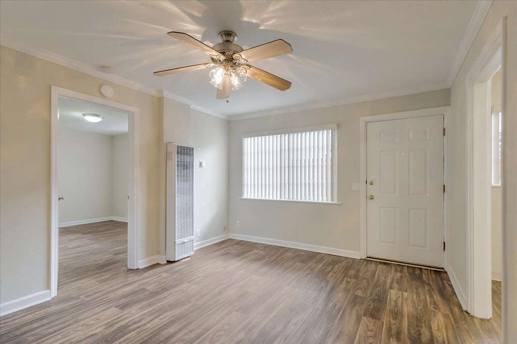 an empty living room with a ceiling fan and a closet