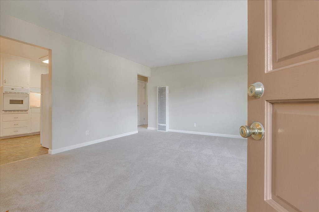 A room with a carpeted floor and a door on the right side.