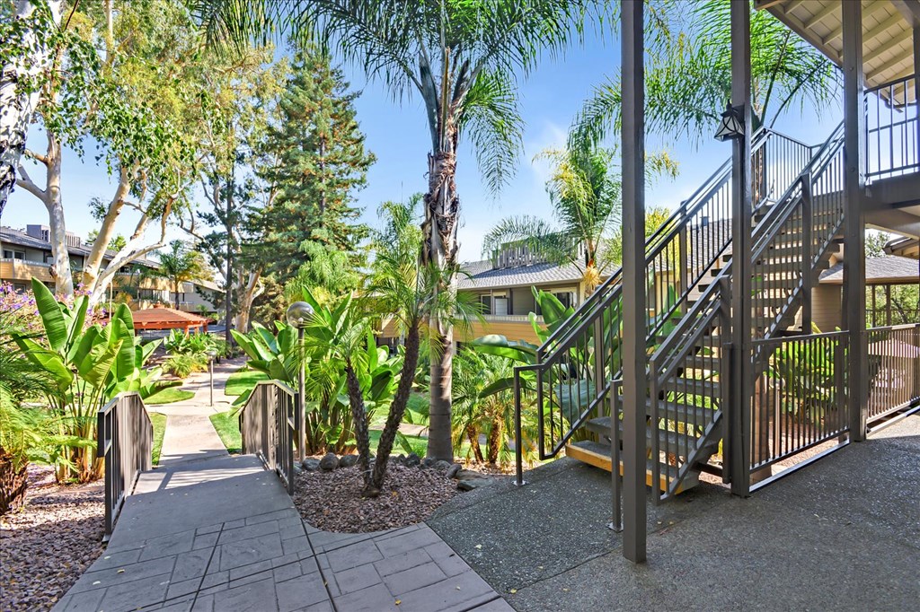 a staircase leading up to a house with trees and plants