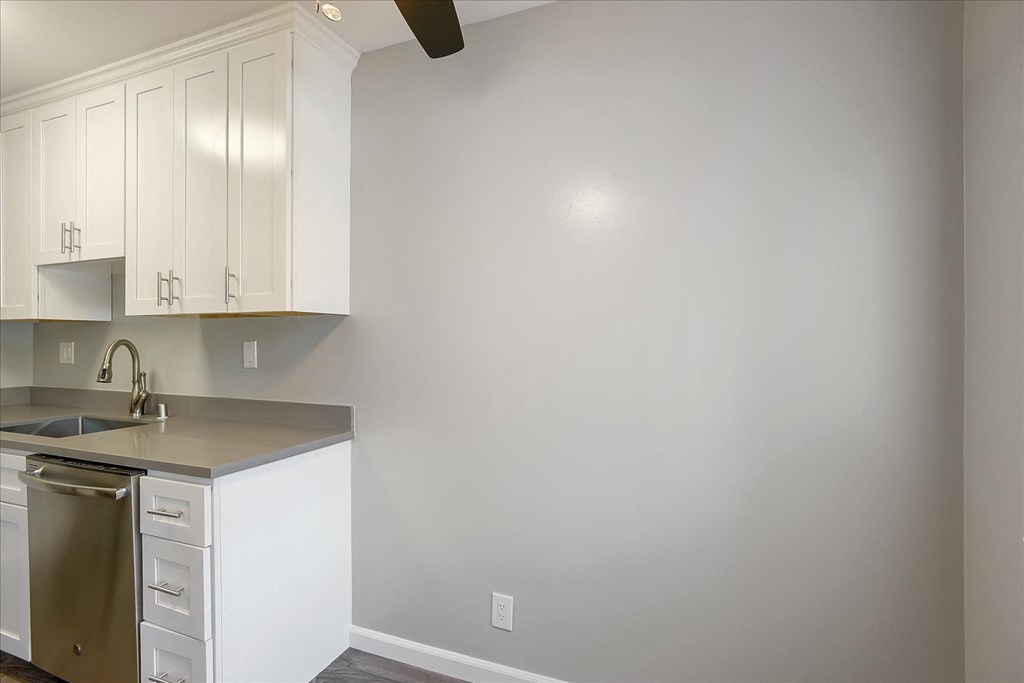 A kitchen with white cabinets and a stainless steel sink.